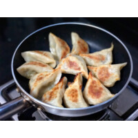煎饺 (jiān jiǎo) : Raviolis frits remplis de porc haché et de légumes