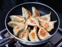 煎饺 (jiān jiǎo) : Raviolis frits remplis de porc haché et de légumes